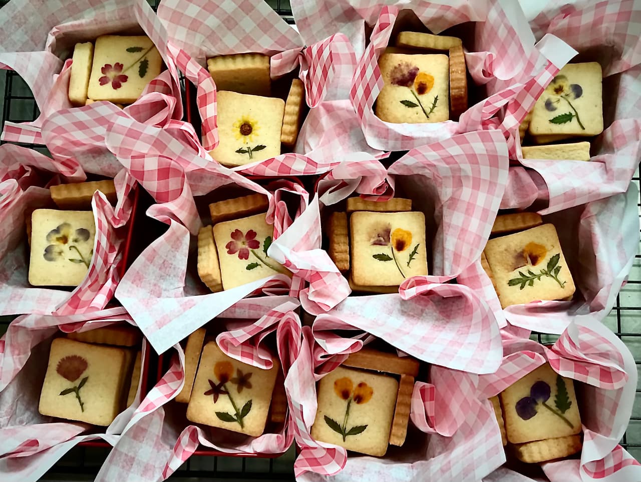 Biscoitos amanteigados decorados com flores comestíveis em uma latinha.